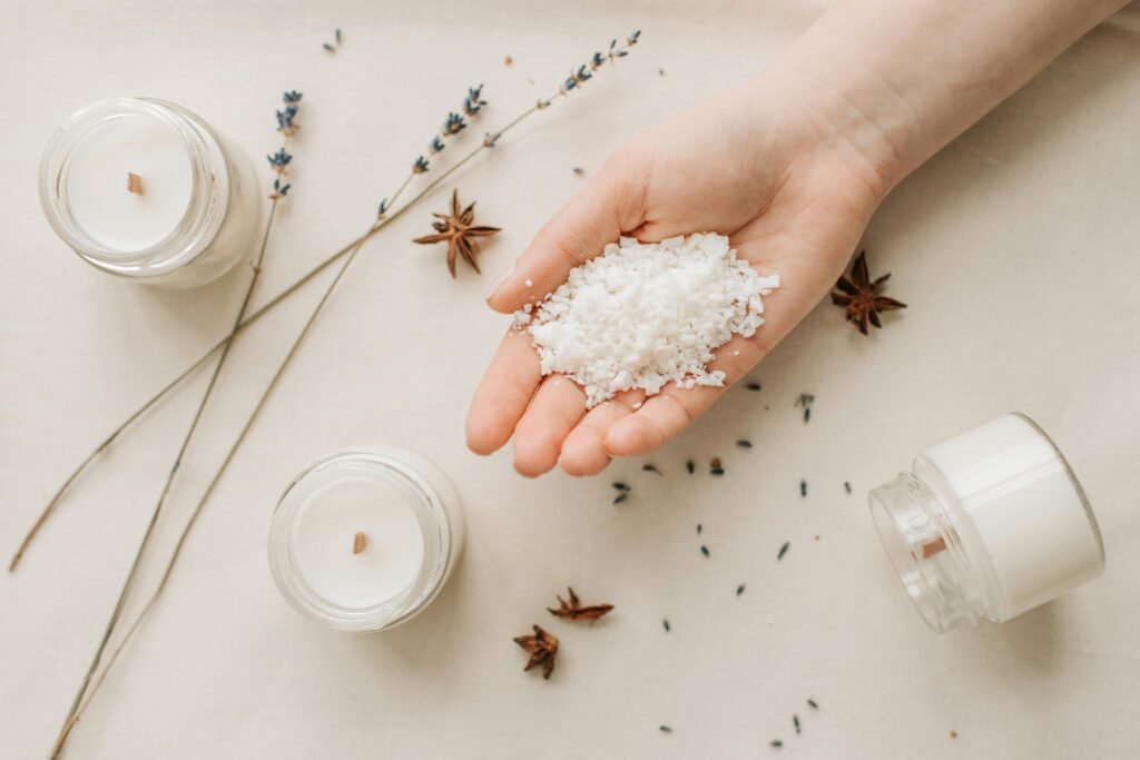 Flat lay of natural candle making with granulated wax, star anise, and lavender on a beige background.